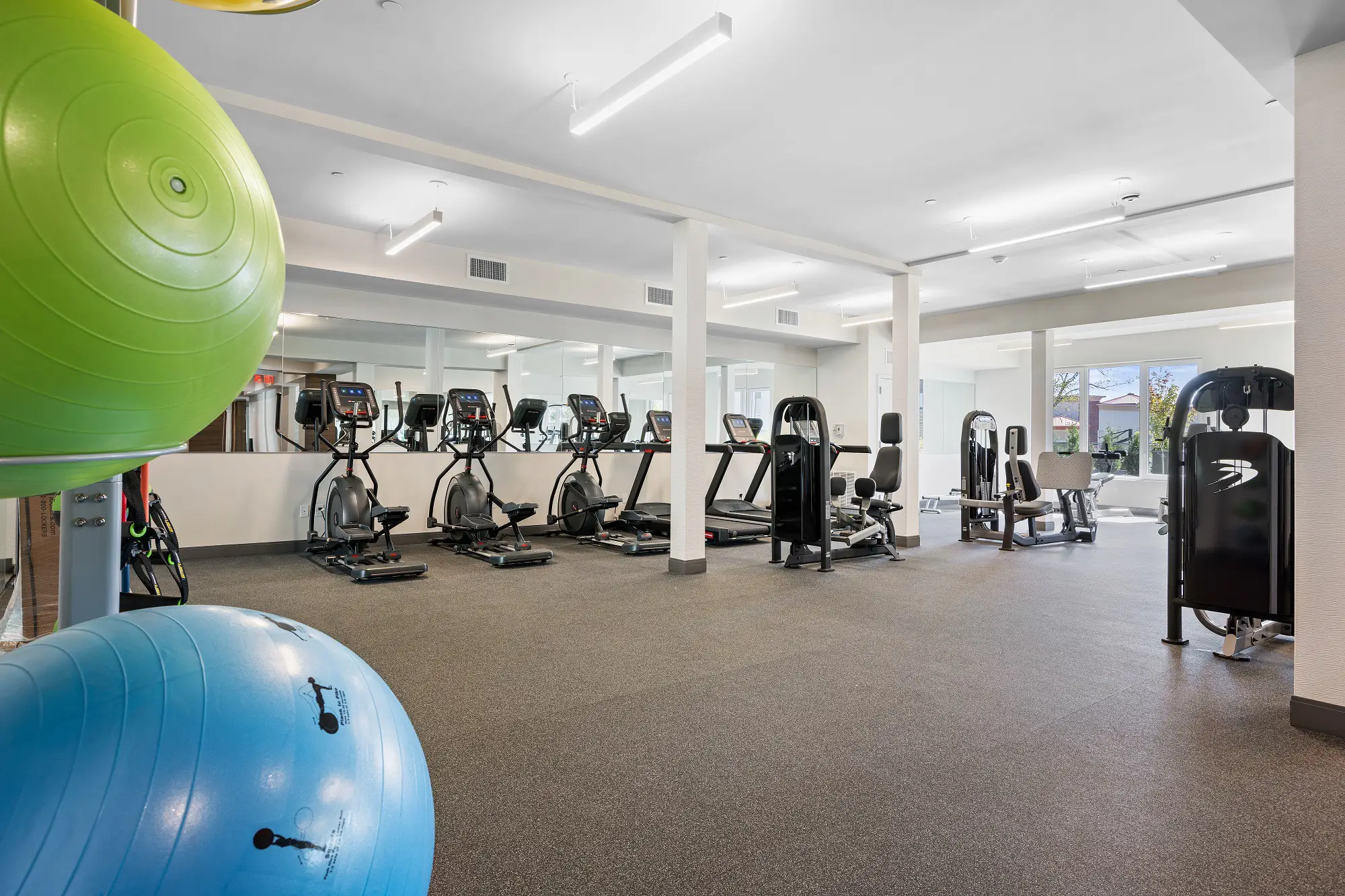 The Beacon fitness center with cardio and weight machines, yoga balls, and a mirror wall