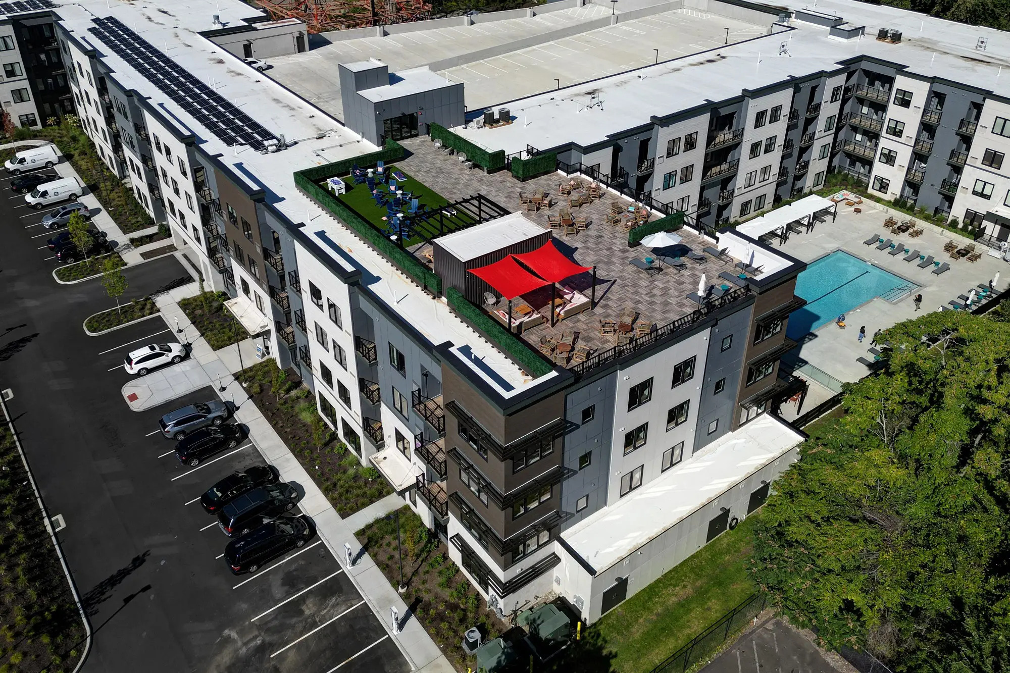The Beacon aerial drone shot of the building corner showing the rooftop amenity deck, the top floor of the parking garage, and the ground floor swimming pool courtyard
