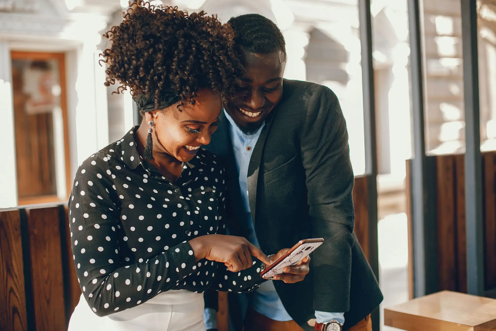 Young and stylish African American black couple smiling while looking at phone